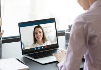 Back view of female talk consult with psychologist or colleague use webcam conference on laptop, woman speak on virtual video call  with business partner or client, online consultation concept